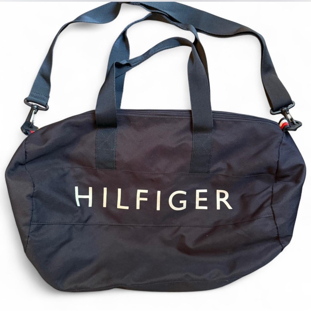 TOMMY HILFIGER lined canvas duffel bag. Handles and shoulder strap with zip top.